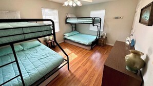 A compact room with two bunk beds, a ceiling fan, a wooden floor, and a small table with a vase. - Bull Shoals Lake House -  Marina & Restaurant Near (Theodosia)