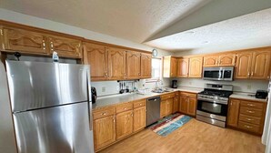 A modern kitchen with wooden cabinets, stainless steel appliances, and a wooden floor. - Bull Shoals Lake House -  Marina & Restaurant Near (Theodosia)