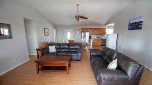A spacious living room with a wooden coffee table, two leather sofas, and a dining area with chairs. - Bull Shoals Lake House -  Marina & Restaurant Near (Theodosia)