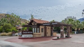 Entrada del Oasis Resort con un letrero visible, una zona de espera techada y vistas del paisaje circundante.