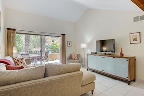 Relax in this serene living space with a sofa, TV, and patio view.