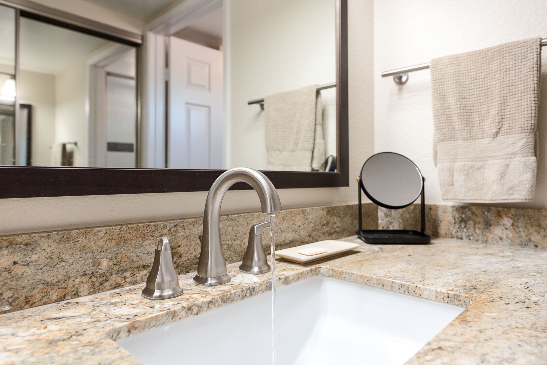 A bathroom with a white sink, a mirror, and a towel rack.