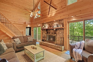 A spacious living room with a stone fireplace, wooden ceiling, and a staircase leading to another level. - Pet Friendly, Fenced Yard, 3 Bedroom Cabin, Hot Tub, 3 Mi. to Beech Ski Resort!  (Beech Mountain)