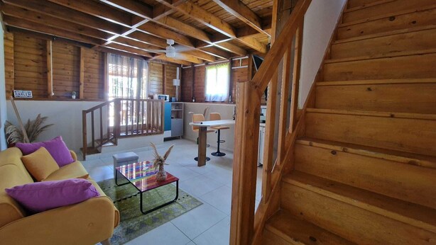 A wooden interior with a sofa, a table, and a staircase.