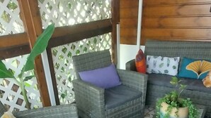 A covered outdoor seating area with wicker furniture and a tiled floor.