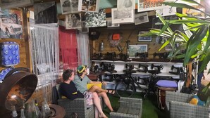 A cozy room with wicker furniture, a sewing machine display, and various photographs on the wall.