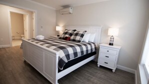 Ein Schlafzimmer mit einem Bett, Nachttischen, einer Lampe und einer Tür zu einem anderen Raum.