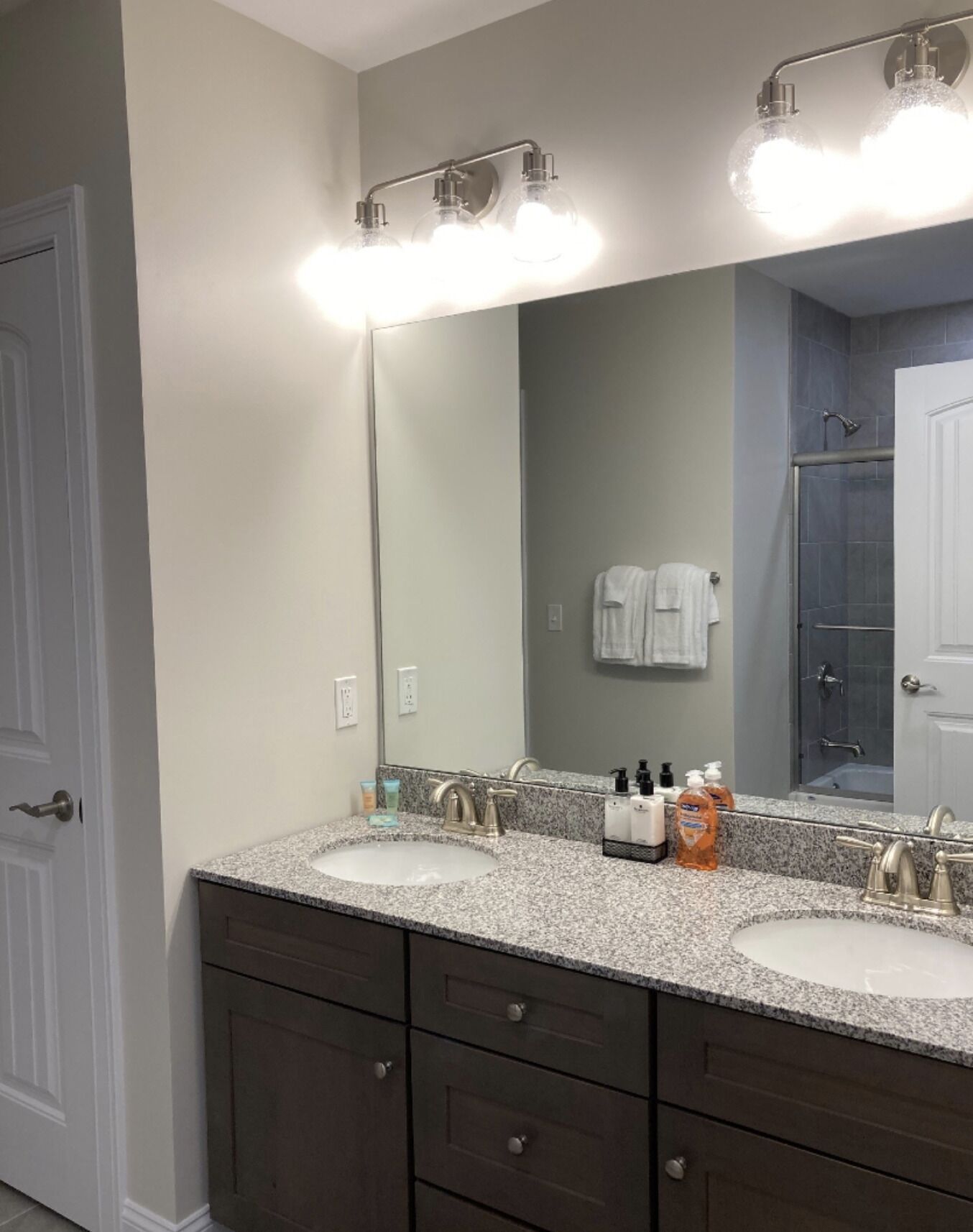 A bathroom with two sinks, a large mirror, and a shower area.