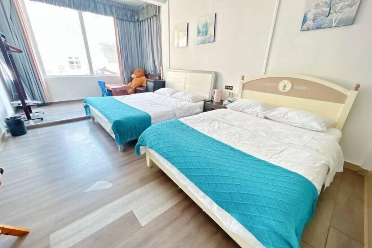 Quarto de hotel com duas camas, uma escrivaninha e uma cadeira.
