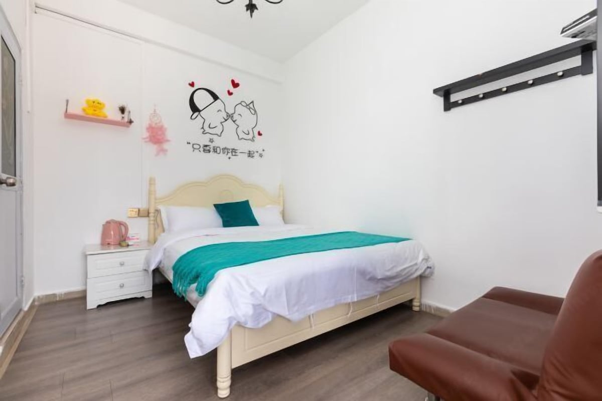 A bedroom with a bed, a nightstand, a chair, a shelf with items, and a wall decoration.