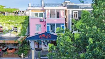 A multi-story building with a pink and blue facade, a covered entrance, and a visible staircase leading to the entrance.
