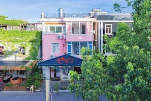 A multi-story building with a pink and blue facade, a covered entrance, and a visible staircase leading to the entrance.