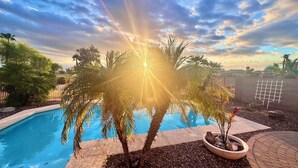 Una piscina circondata da palme e da un muro in mattoni.