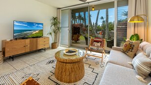 Un salon moderne avec une grande télévision, une table basse ronde en bois, un canap é et un fauteuil.