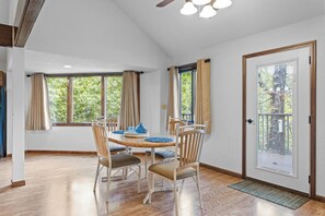 A dining area with a wooden table and chairs, large windows with curtains, and a door with a metal gate. - Holiday Shores 18 - Three Bedroom Villa, Sleeps 8 (Osage Beach)