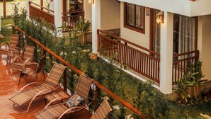 A two-story wooden building with balconies, outdoor seating, and a view of a forested hillside. - Pousada Rosa Maria (Imbituba)