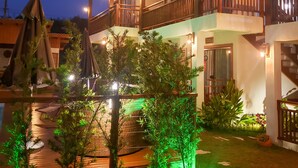 A multi-story hotel with balconies, outdoor lighting, and a pool area. - Pousada Rosa Maria (Imbituba)