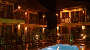 A hotel with a pool area, multiple balconies, and outdoor seating. - Pousada Rosa Maria (Imbituba)