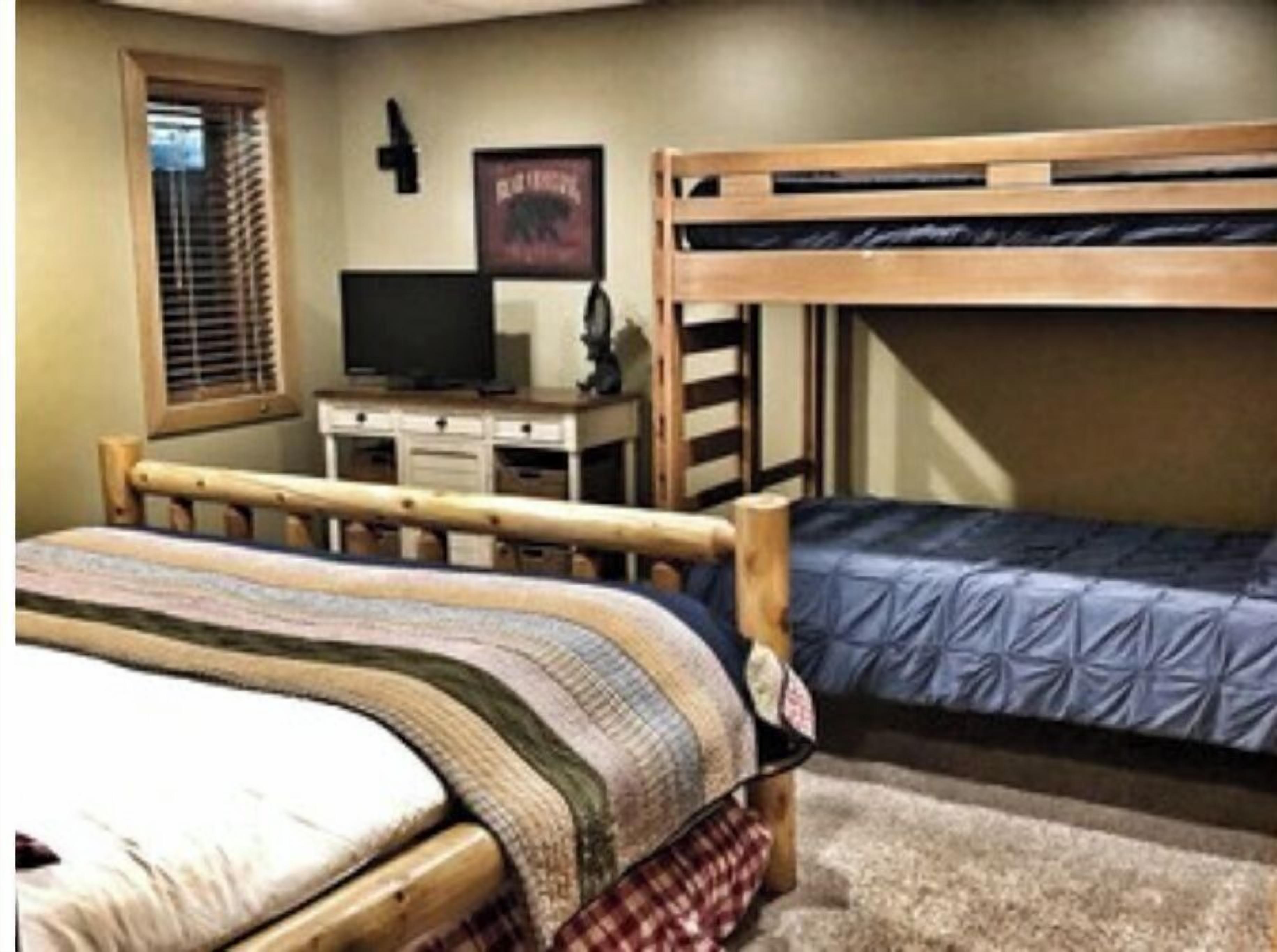 Een slaapkamer met een stapelbed, bureau en televisie.