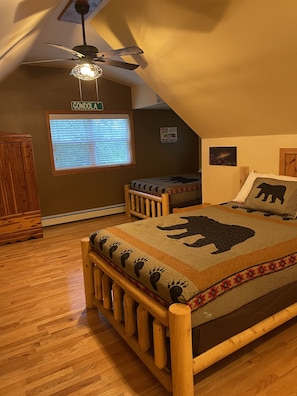 Cozy attic bedroom with a wooden bed, ceiling fan, and window with blinds.