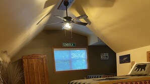 A cozy attic bedroom with a sloped ceiling, a wooden bed, a ceiling fan, and a window with blinds. - Rush Hollow Hideaway (Lake George)