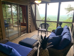 Un espacio de estar techado al aire libre con mobiliario de mimbre y vistas a un paisaje montañoso.