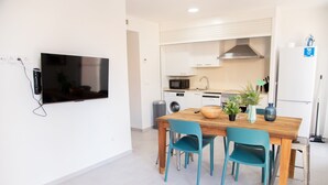 Una cocina moderna con una mesa de comedor de madera, sillas color azul verdoso, un microondas, una lavadora y un refrigerador.