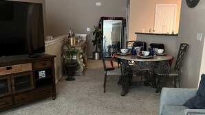 A living room with a television, a dining table with chairs, a sofa, and a decorative mirror. - Cozy, Cool & Central location to the Galleria and NRG stadium (Houston)