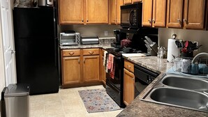 A kitchen with wooden cabinets, a black refrigerator, a microwave, a stove, and a sink. - Cozy, Cool & Central location to the Galleria and NRG stadium (Houston)