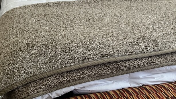 A neatly made bed with a tufted headboard, a patterned throw blanket, and a striped carpet. - Cozy, Cool & Central location to the Galleria and NRG stadium (Houston)