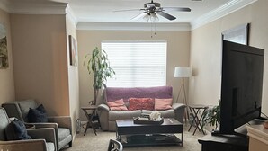 A living room with a sofa, coffee table, TV, and a dining area with chairs and a table. - Cozy, Cool & Central location to the Galleria and NRG stadium (Houston)