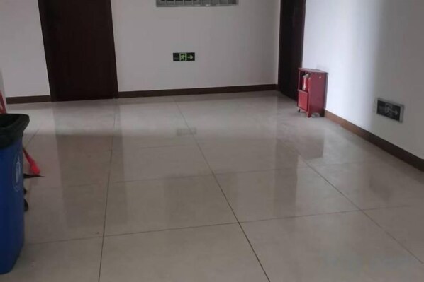 A hallway with a tiled floor, a door, and a red cabinet.