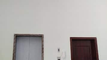 A plain wall with two doors, one with a visible electrical outlet and switch, and another with a phone.