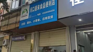A storefront with a blue signboard displaying the name and contact information of a convenience store.