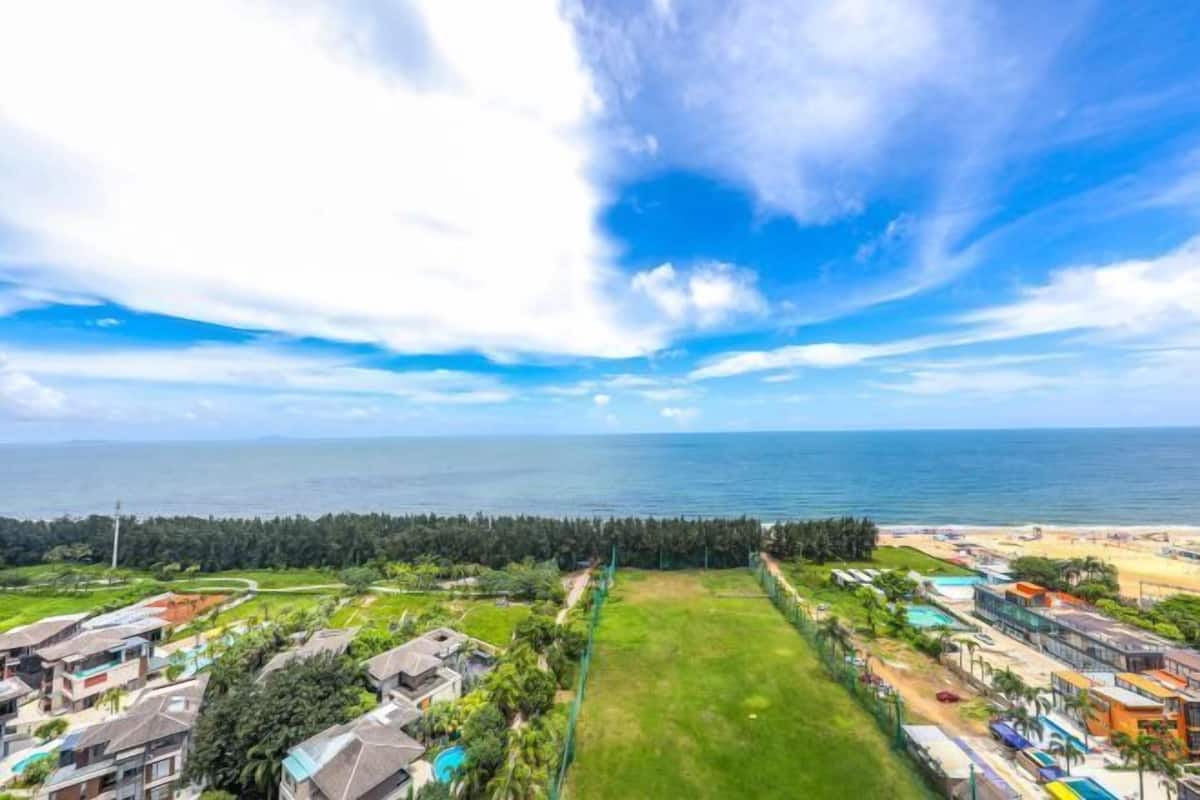 A coastal property with a view of the sea, a grassy area, and a beach.