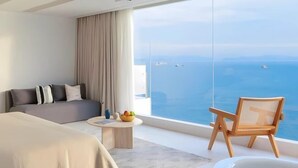 A modern hotel room with a large bed, a seating area with a view of the sea, and a small round table with fruit. - Lantian Weekend Vacation Homestay (Yangjiang Hailing Island Poly Silver Beach) (Yangjiang)