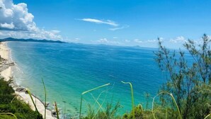 A coastal landscape with clear blue waters, a sandy beach, and distant mountains under a bright blue sky. - Lantian Weekend Vacation Homestay (Yangjiang Hailing Island Poly Silver Beach) (Yangjiang)