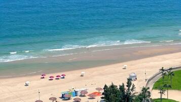 A beach with umbrellas and beach chairs, a clear sky, and the ocean.