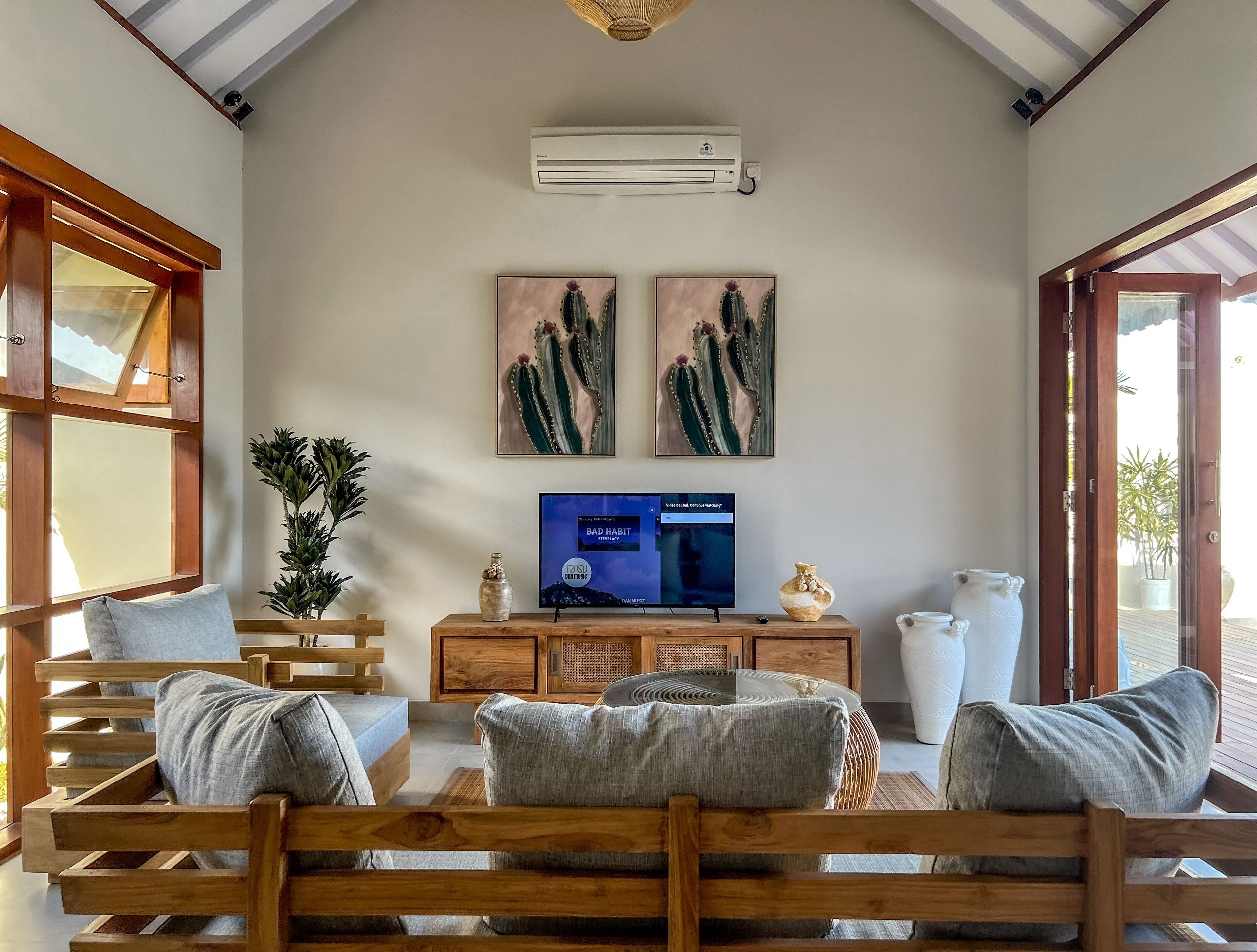 A cozy living room with wooden furniture, a flat-screen TV, and artwork on the wall.