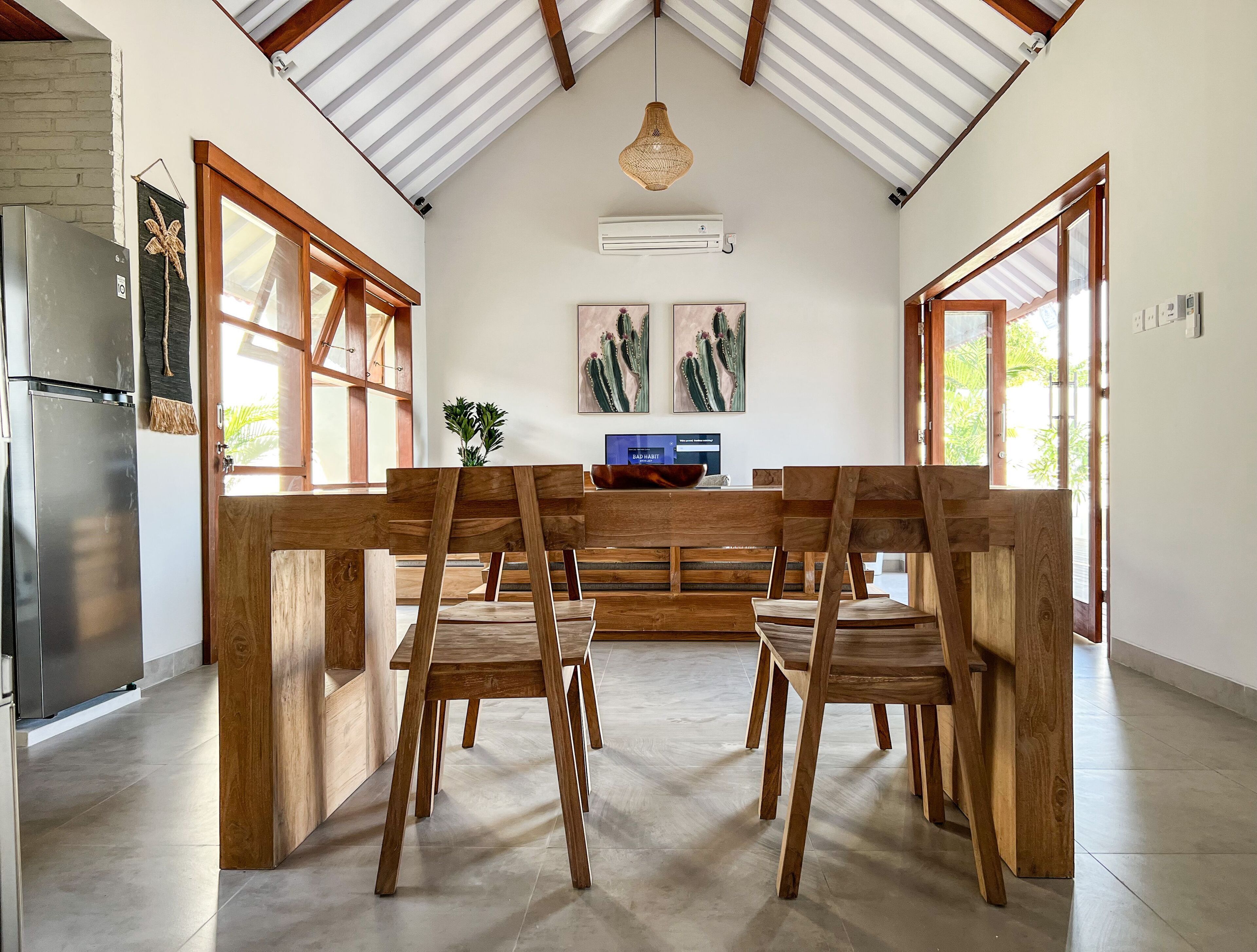 A spacious kitchen with a wooden dining table, chairs, and a modern refrigerator.