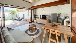 Uma cozinha moderna com televisão, frigorífico e área de refeições com mesa e cadeiras de madeira.