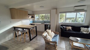 Een compacte leefruimte met een kitchenette, een eethoek, een bank en een klein tafeltje.