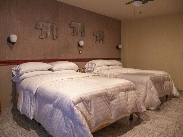 A hotel room with two beds, a wooden headboard, wall-mounted light fixtures, and a ceiling fan. - Hotel el Cóndor (Cortazar)