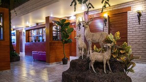 A lobby with a reception desk, a seating area, and a decorative rock with animal statues. - Hotel el Cóndor (Cortazar)