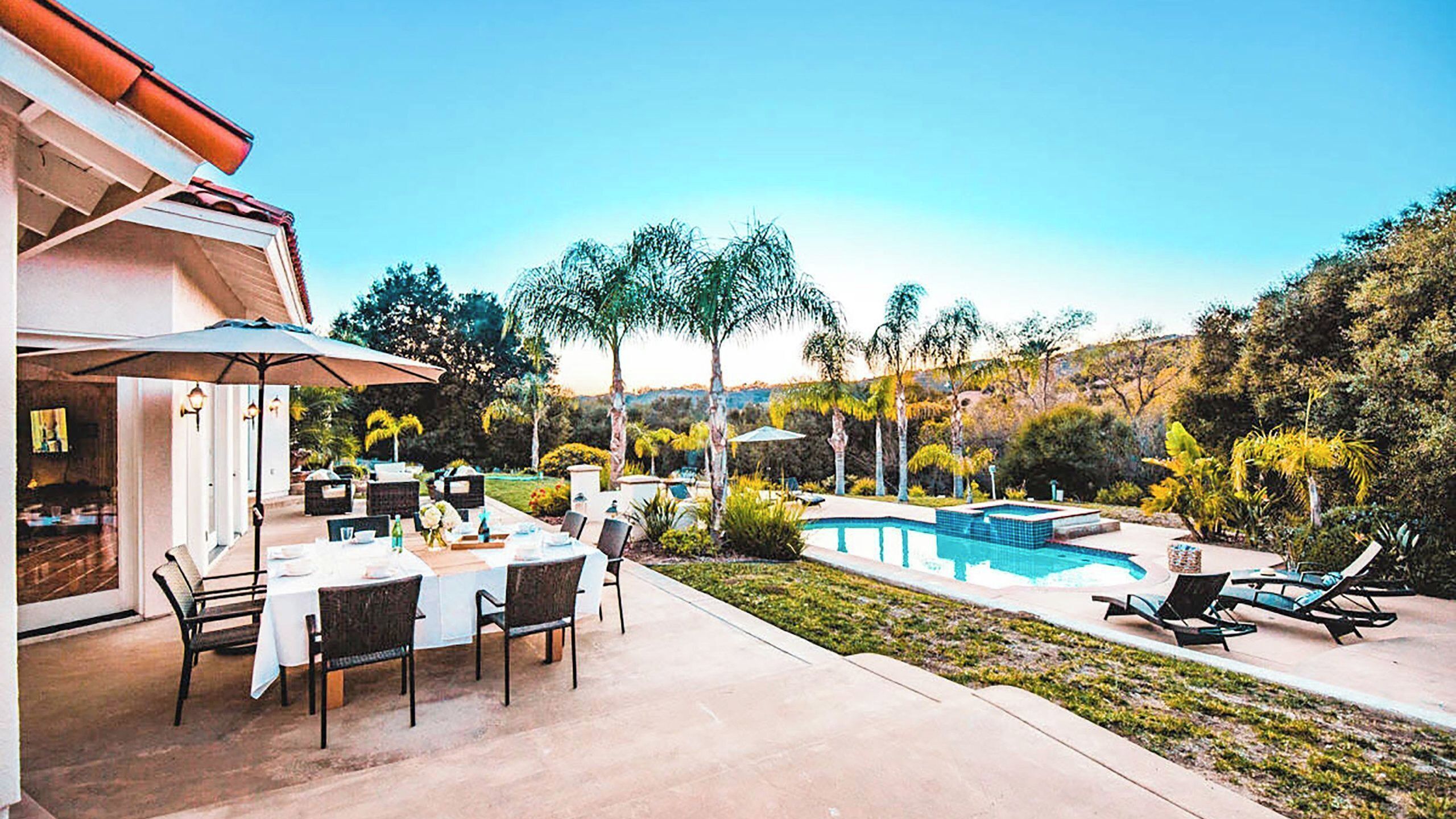 A patio with a pool, outdoor seating, and a view of the surrounding landscape.