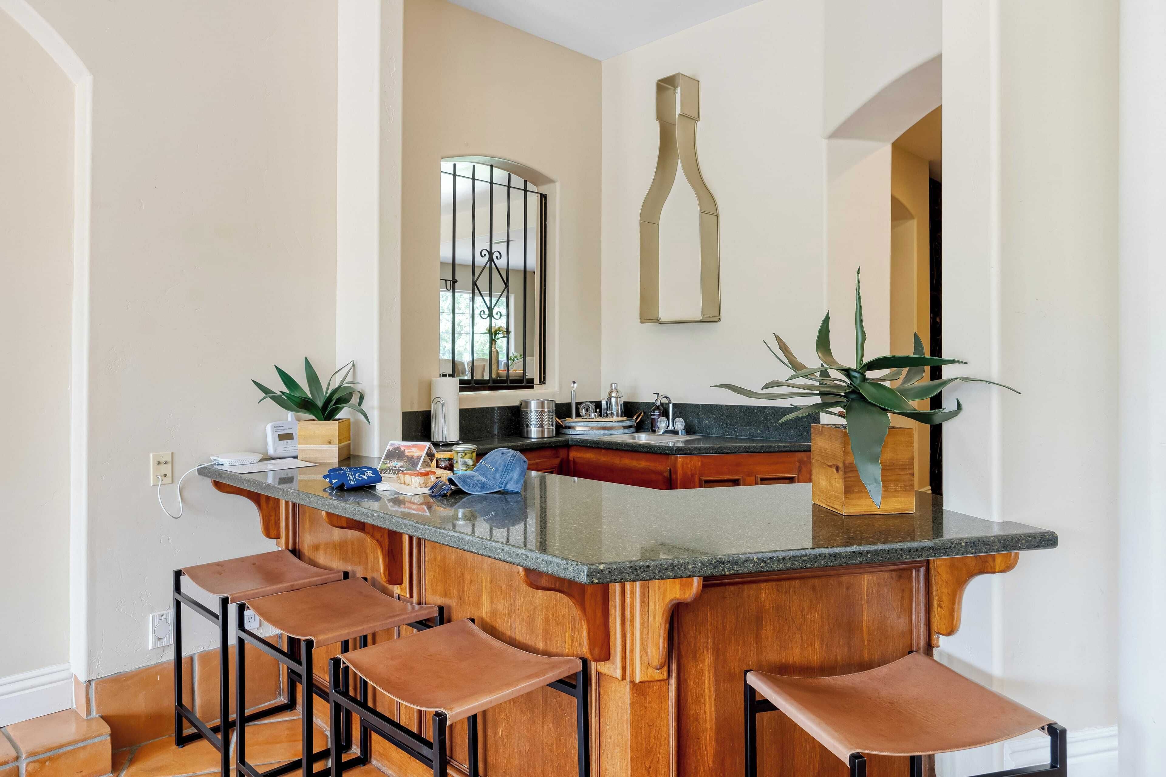 Une cuisine dotée d’un îlot central, de tabourets de bar et d’une décoration en forme de bouteille de vin.