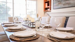 A dining table set with plates, cutlery, and wine glasses, with a bottle of wine and candles. - Grapevine by Avantstay Secluded 5BR Villa 4 Acres of Vineyards & Avo Groves! (Temecula)
