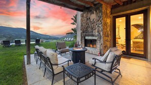 An outdoor patio with stone walls, a fire pit, and outdoor seating.