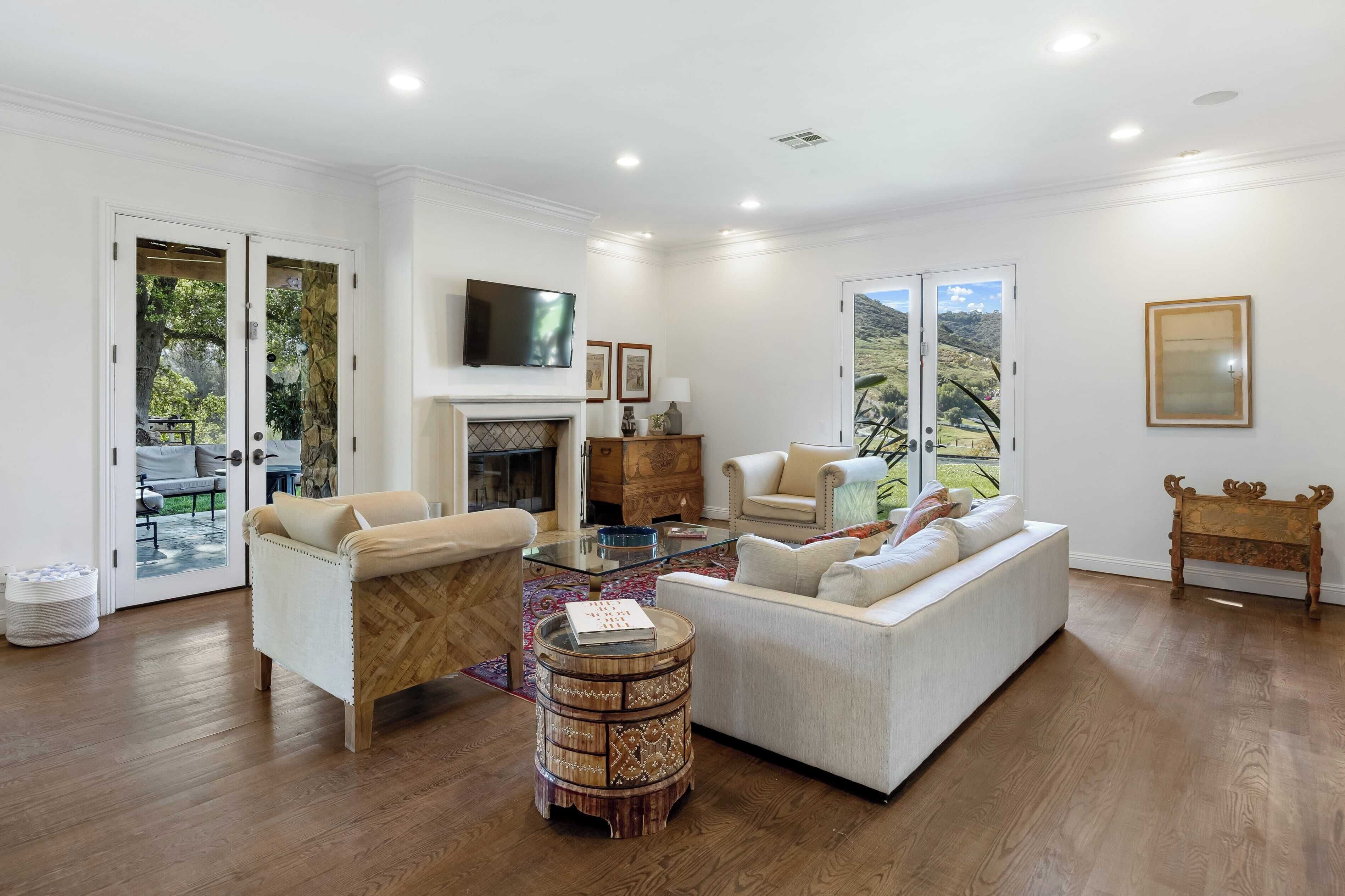 A spacious living room with a fireplace, comfortable seating, and a large TV.