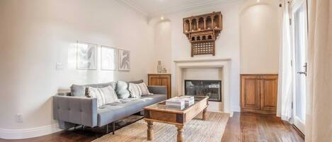 A living room with a grey sofa, wooden coffee table, and a fireplace.